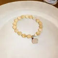 Detailed view of a New Chinese style beaded bracelet with a delicate pale pink flower charm - Light Yellow