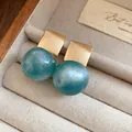 Close-up detail of candy-colored teal resin ball earrings with brushed gold squares - Gold-Blue