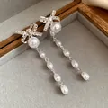 Primo piano di orecchini a fiocco in argento con lunghe nappe di perle bianche - Stile Fiocco Perla (9#)