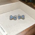 Primer plano de elegantes pendientes de lazo de plata con incrustación azul - Azul Mariposa (39#)