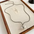 Elegant silver-toned gourd pendant necklace on a black cord displayed on a wooden linen tray - 29# Necklace - Silver
