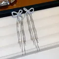Detailed close-up of elegant silver bowknot earrings with sparkling zircon long tassels - Bow Tassel / Silver