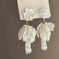 Primer plano de pendientes de flores blancas con pétalos nacarados y cuentas finas - Blanco Flor (16#)