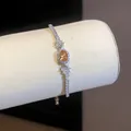 Dettaglio ravvicinato di un bracciale argento con zircone arancione ovale e pavé - Argento-Caffè