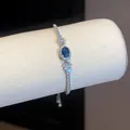 Dettaglio di un elegante bracciale con zircone blu ovale e accenti scintillanti. - Argento-Blu