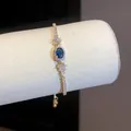 Vista dettagliata di un elegante bracciale in oro con zircone blu ovale e cristalli - Oro-Blu
