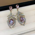 Close-up view of elegant pink crystal feather earrings with rhinestones in vintage style. - Hollow Feather Style / Gold Plated Pink