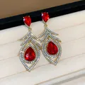 Close-up of retro palace style earrings with red crystals and feather rhinestones - Hollow Feather Style / Gold with Red