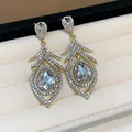 Close-up of vintage gold hollow feather earrings encrusted with sparkling crystals - Hollow Feather Style / Gold With Clear