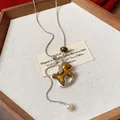 Detailansicht des goldenen Schaukelpferd-Anhängers und der Perle an Silberkette - Silber-Gelb