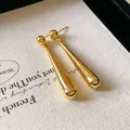 Close-up of elegant gold waterdrop earrings with a high-polished metallic finish - Gold