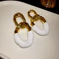 Vista detallada de pendientes de eslabones ovales dorados con pliegues blancos y aguja plata - Estilo Plisado Hueco Ovalado / Dorado