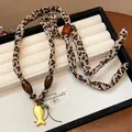 Primo piano di una collana in tessuto leopardato con perle di legno e ciondolo a pesce d'oro. - Ciondolo Pesce Leopardato / Oro