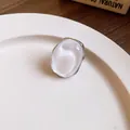 Detail of a pearlescent oval stud earring with silver needle on a ceramic plate. - Oval Pearl Luster Ring / Silver White
