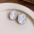 Macro view of elegant oval pearl luster stud earrings with silver-toned metallic edges - Oval Pearl Luster Stud Earrings / Silver White