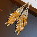 Primo piano di eleganti orecchini a pendente vintage dorati con brillanti cristalli ambrati - Stile Nappine Foglia Ambra (10#)
