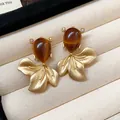 Close-up detail of vintage goldfish earrings with brown teardrop stones and textured gold fins - Gold/Brown
