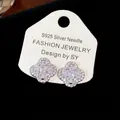 Exquisite close-up of sparkling cubic zirconia flower stud earrings on a display card - Clip-On Earrings / Silver
