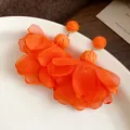 Primo piano dettagliato di orecchini a fiore in chiffon arancione con dettagli in rafia - Orecchini pendenti / Arancione