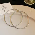 Detail view of minimalist oversized silver hoop earrings displayed on a cream ceramic plate - Shiny Silver Plain Style / 7cm / Silver