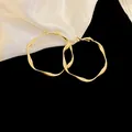 Macro view of elegant golden twisted hoop earrings displayed on white satin fabric - Style(44#) / Medium / Gold