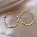 Close-up view showing the elegant golden faceted texture on large round hoop earrings - Style 52 / Gold