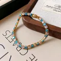 Detailed close-up view of gold-plated evil eye bracelet with square-cut clear zircons - Light Blue
