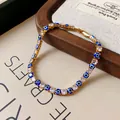 Close-up detail of a gold-tone bracelet with square CZ and blue evil eye charms. - Blue
