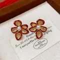 Detailed macro view of red enamel flower stud earrings with central pearl and gold plating - Textured Pearl Style (1#) / Gold Red