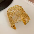 Detailed macro shot of gold woven mesh open cuff bracelet with metallic luster - Cross / Gold