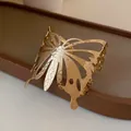 Macro detail of a gold-plated butterfly cuff bracelet featuring a hammered metal texture. - Gold Hammered Butterfly Hollow Style (HB2501)