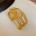 Close-up detail showing the intricate multi-strand gold woven design of this open cuff bracelet - Bow / Gold