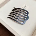 Close-up detail of a minimalist matte black wave-shaped U hair comb for bun styling. - Seven-Tooth Wave Hair Comb (HH8838) / Matte Black