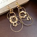 Detailed view of gold knot earrings with layered hammered circle tassels - Knot Round Tassel (HE28767) / Gold