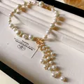 Detailansicht der eleganten Perlen-Blumen-Quastenkette auf einem Samt-Schmuckdisplay - Blumen-Quasten-Halskette / Gold+Weiß