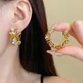 Macro view of elegant golden flower hoop earrings with crystal centers worn by model - 24# Daisy-Shaped Flower Tassel Style / Gold