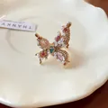 Close-up detail of a butterfly ring with pearls and pink crystals on a white plate - Butterfly Design / Gold