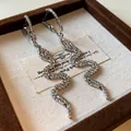 Close-up detail of silver snake-shaped dangling earrings paved with sparkling crystals - Silver Post - Geometric Snake / Silver