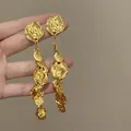 Detailed view of gold wrinkled metal disc tassel earrings with a textured finish - Long Metal Disc Tassel Style / Gold