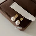 Detailed view of 8mm round white pearl stud earrings with gold finish posts - 8mm / Gold (White Pearl)