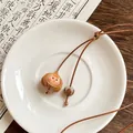 Close-up of retro wax rope necklace with wooden pinecone pendant on a white saucer - Garlic Style (2#)