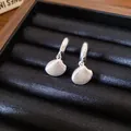 Primo piano di eleganti orecchini a conchiglia in argento su un vassoio di velluto nero - Conchiglia / Argento