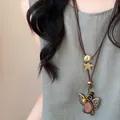 Gros plan d'un collier vintage en corde cirée avec perle en bois et pendentif papillon - Style Papillon Ajouré (10#)