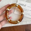Detail view of a vintage amber acrylic bracelet with elegant gold-tone metal spacers. - Dark Coffee