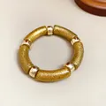 Detailed view of a gold glitter acrylic tube bracelet with shiny metallic spacer beads. - Gold