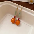 Macro detail of Chinese style resin persimmon earrings with green stone beads - Hook Style / Orange