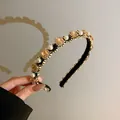 Close-up detail of a fashionable headband with pearls and amber rhinestones set in gold - Champagne