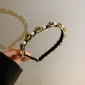Close-up of elegant pearl and grey rhinestone headband with gold braided details - Black