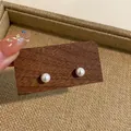 Close-up shot of elegant round pearl stud earrings displayed on a rustic wooden board - Imitation Shell Pearl (HE8071) / 8mm/Pack