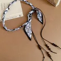 Detailed macro view of vintage paisley fabric waist chain featuring dark brown beaded tassels - Style 35#